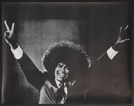 a man (Richard Nixon) with afro hair raising his hands shaped into peace signs