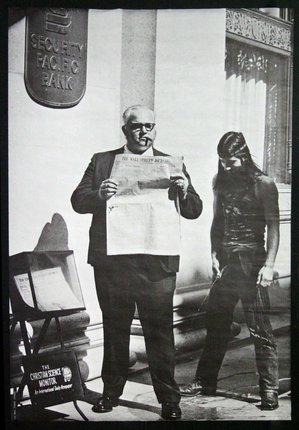 a man reading a newspaper next to a man