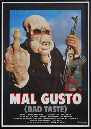 movie poster with a mutant alien man holding an automatic rifle and holding up his middle finger