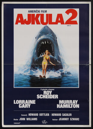 a movie poster with a woman in the water on water skis and a shark with an open mouth and sharp teeth emerging from the wake behind her