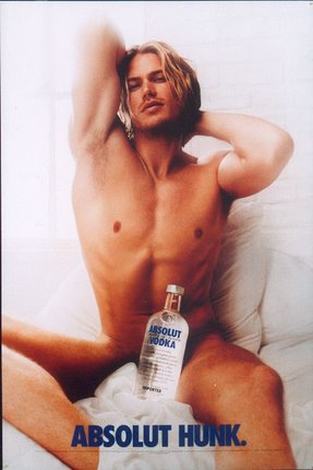 a man sitting on a bed with a bottle of vodka