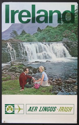 a man and woman sitting on rocks by a waterfall