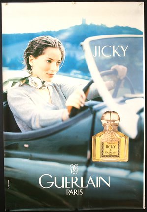 a woman driving a car with a bottle of perfume