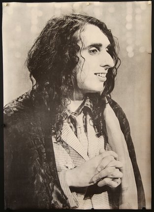 a man with long hair and a scarf holding his hands together