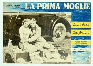 a man and woman sitting on a blanket in front of a car