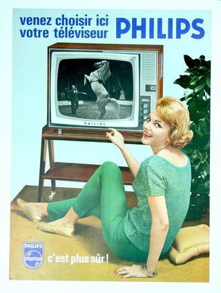 a woman sitting on the floor pointing at a television