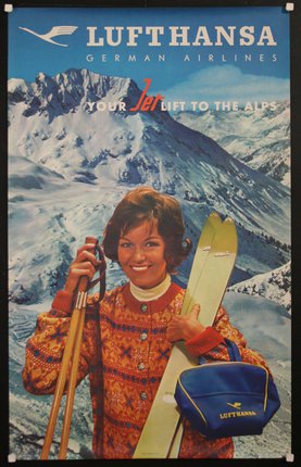 a woman holding skis and poles in front of a snowy mountain