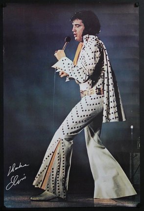Elvis in a distinctive white bell bottomed suit holding a microphone