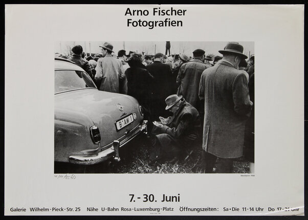 black and white photograph of a group of people next to a car