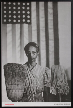 photo of a woman holding a broom and mop while standing in front of an American flag