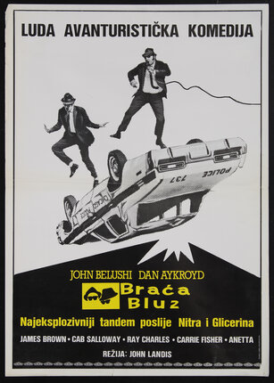 movie poster with two men in black suits jumping on a flipped over police car