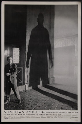 a man standing next to a looming shadow of another man on the wall beside him